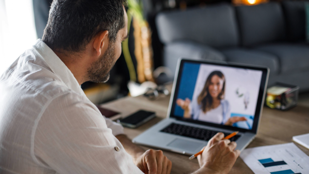A businessman interviews a happy customer on a video call to learn more about how the customer feels about the company and how they compare to competitors.